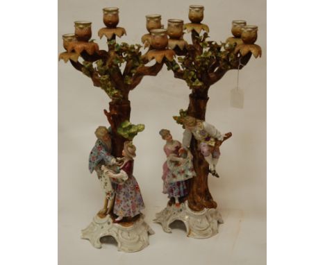 A pair of circa 1900 Sitzendorf porcelain five-light candelabra, each modelled as trees with attendant courting couples, the 