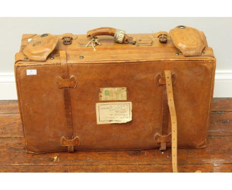 A vintage tan leather suitcase with leather straps, metal locks and labels to lid, 64cm wide 