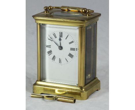 A brass carriage clock with exposed platform escapement, the white enamel dial with Roman numerals denoting hours and raised 