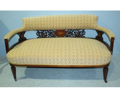 An Edwardian inlaid mahogany two-seater sofa with pierced and carved floral back, cream fabric upholstered seat and raised on