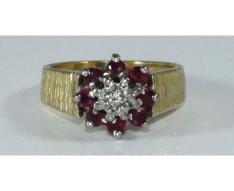 An 18ct gold, ruby and diamond ring, textured shank, illusion-set diamond surrounded by eight rubies, 6.23 grams 