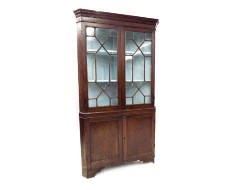 Georgian oak and mahogany freestanding corner cabinet, the top with twin astragal glazed doors over a base fitted with panel 