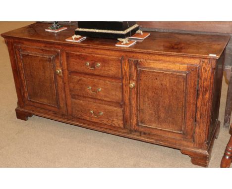 A Mid 18th Century Enclosed Oak Dresser, with a central bank of three drawers flanked by moulded cupboard doors above a mould