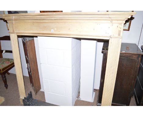 A stripped pine fire surround with flared cornice and reeded pilasters.