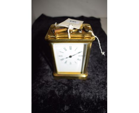 A brass carriage clock with enamel dial and Roman numerals.