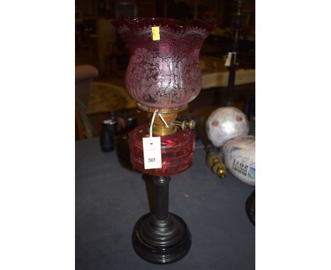 A late Victorian cranberry glass oil lamp, raised on Corinthian column painted base.