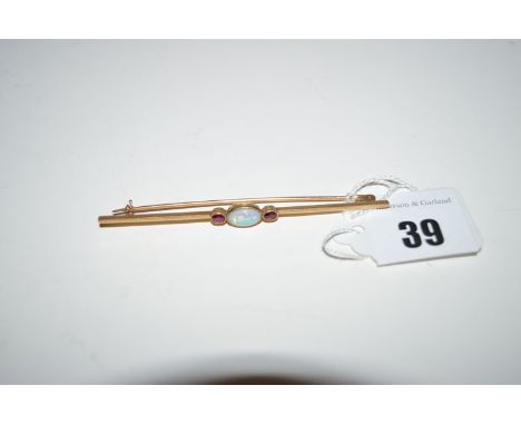 An opal and ruby bar brooch, the oval cabouchon opal flanked by two facet cut rubies, all in millegrain mount, oak leaf stamp