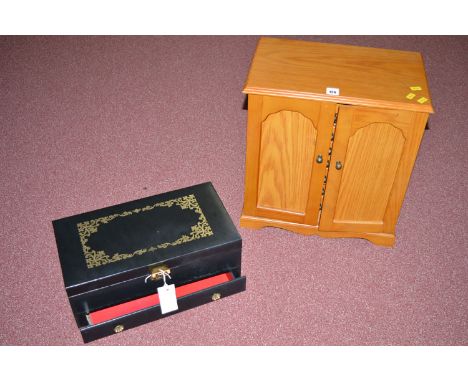 A light stained wood jewellery cabinet, the panel doors opening to reveal seven drawers; together with a leatherette jeweller