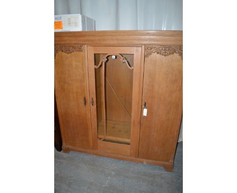 An oak bookcase/display cabinet, the centre glazed panel door flanked by doors with carved decoration and enclosing shelves, 