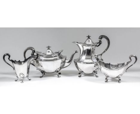 A George V silver oval four piece tea service of panelled form, with scroll mounts, high scroll handles and on leaf cast and 