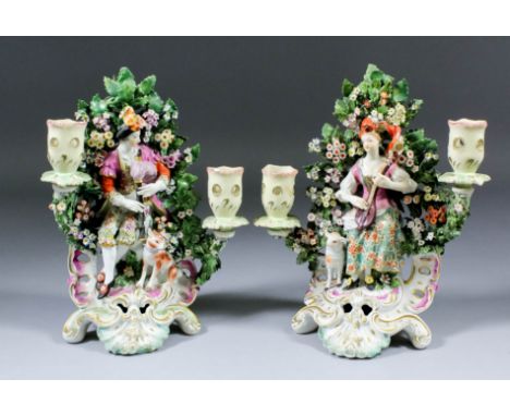 A pair of 18th Century Derby porcelain candlestick groups modelled as male and female musicians against bocage, each 9.75ins 