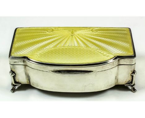 A George V silver rectangular bow front jewellery box with yellow guilloche enamel panel to top, cloth lined interior, on fou