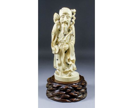 A Japanese large carved ivory Okimono of a standing bearded sage wearing cap and long flowing robes, carved, inlaid and appli