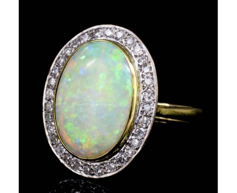 A modern 18ct gold mounted opal and diamond ring, the oval cut opal of approximately 4.50ct surrounded by thirty small rose c