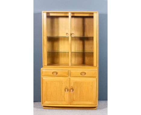 A modern Ercol blonde elm "Windsor" display cabinet, the upper part fitted two plate glass shelves, enclosed by a pair of gla