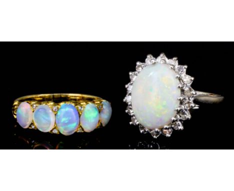 A modern 18ct white gold mounted opal and diamond ring, the oval cut opal of approximately 4ct, surrounded by eighteen small 