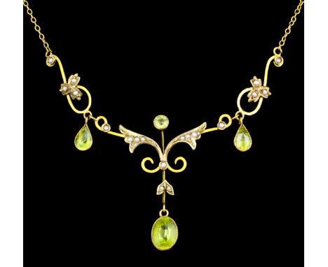 An Edwardian gold coloured metal mounted peridot and seed pearl necklace, the scrolling form set with three tear cut peridots