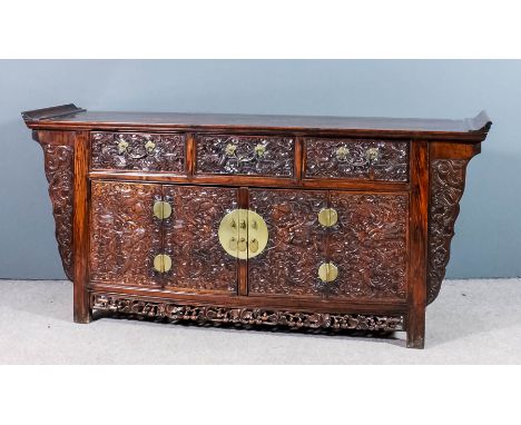 A Chinese rosewood sideboard with flush panelled top and scroll ends, the front carved with dragons and cloud motifs, three f