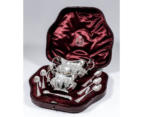 A late Victorian silver oval two-handled sugar basin and matching cream jug with shaped rims, the lobed bodies cast with scro