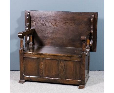 A panelled oak "Monks" bench with plain folding top, box seat and with three panel front, on trestle feet, 42ins wide x 22ins