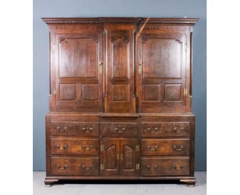 A mid-18th Century panelled oak break-front "Housekeepers" cabinet, the upper part with moulded dentil cornice, fitted turned