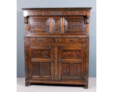An early 18th Century panelled oak court cupboard, the upper part with overhanging frieze with moulded cornice, carved with s