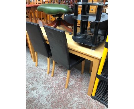 A light wood dining table and 4 leather effect chairs 