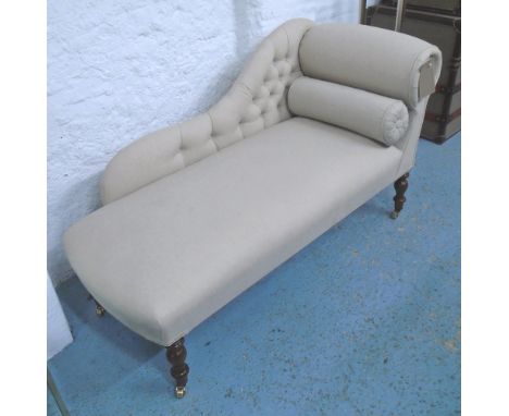 CHAISE LONGUE, in neutral button back fabric on turned castor supports, 130cm L.