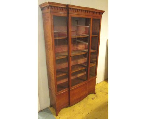 BREAKFRONT BOOKCASE, Edwardian satinwood with a central glazed door enclosing shelves over a panelled door on swept bracket f
