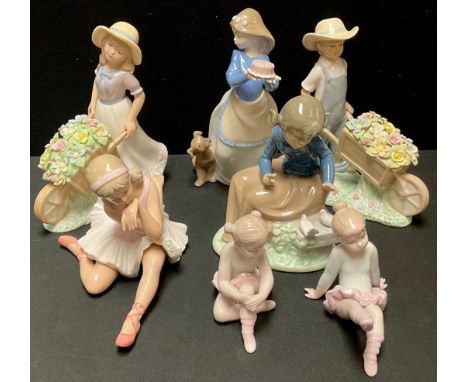 A Spanish Nao figure girl with cake and puppy, 20cm; another girl with doves; three porcelain ballerina girl figures, Leonard