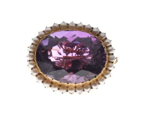 Oval amethyst coloured faceted stone brooch set within a gilt metal seed pearl border   Condition: 