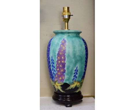 Crown Devon ovoid lamp base having stylised foliate decoration on a mottled green ground and standing on a black wooden base 