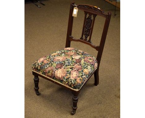 Edwardian carved walnut nursing chair, the stuffed seat upholstered in floral patterned simulated tapestry and standing on ta