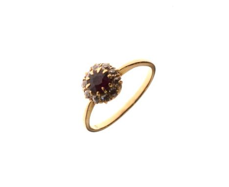 Dress ring set central ruby coloured stone with a diamond surround, the shank stamped 18ct, size M   Condition: 