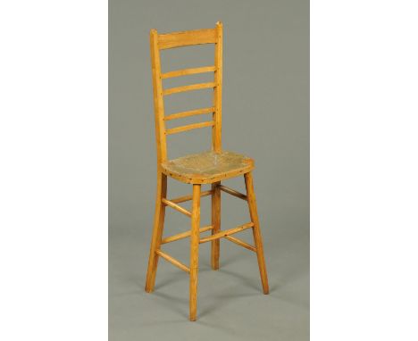 A Victorian oak child's high or correction chair, with rush seat and ladder back.  