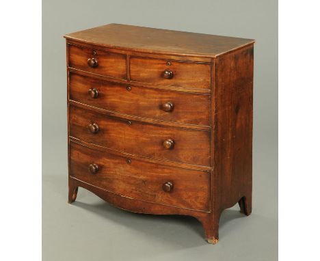 An early 19th century mahogany bowfronted chest of drawers, two short and three long drawers with wooden knob handles and rai