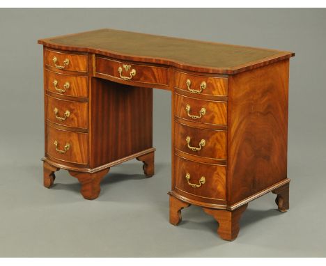A Reprodux pedestal desk, mahogany, fitted with a frieze drawer, with four further drawers to each pedestal and raised on bra