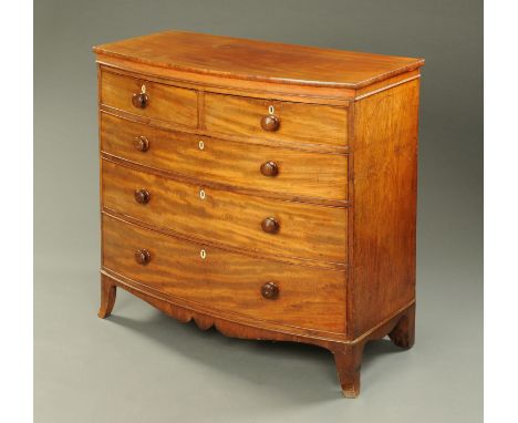 An early 19th century mahogany bow fronted chest of drawers, with two short and three long drawers with wooden knob handles a