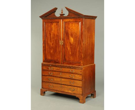 A George III mahogany linen press, with detachable broken pediment above a pair of panelled doors enclosing shelves and drawe