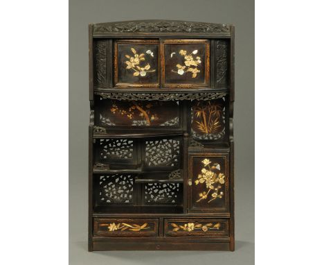 An Oriental carved wooden shelf and cupboard unit, with applied bone and mother of pearl foliate decoration.  Width 57 cm, he