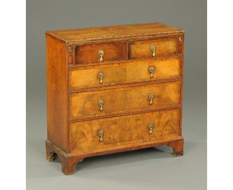 A walnut bachelor's chest, circa 1930, with fold over top and fitted with two short and three long drawers with brass drop ha