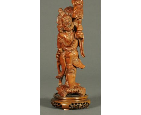 A Chinese wooden carving of a figure, raised on a wooden stand and converted to a table lamp, height excluding light fitting 