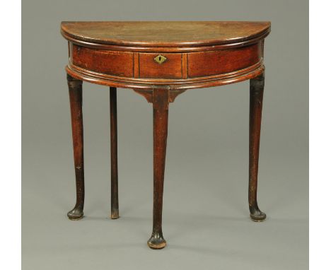 A Queen Anne red walnut demi-lune turnover top tea table, fitted with a drawer and raised on turned legs terminating in pad f