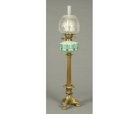 A Victorian brass column oil lamp, with blue glass reservoir, etched glass shade and raised on a triform base with three paw 