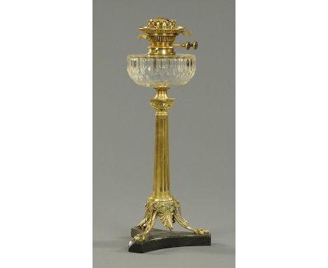 A Victorian brass oil lamp, with clear glass reservoir and raised on a black slate base.  