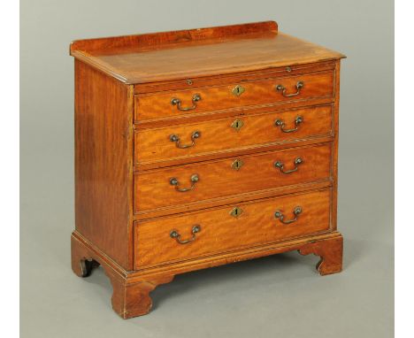 A George III mahogany chest of drawers, with crossbanded edge above a slide and four long graduated drawers with brass drop h