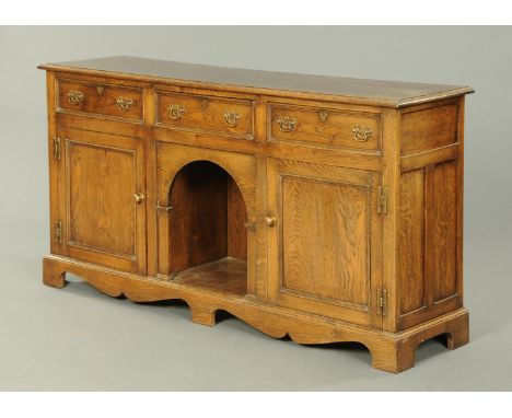 An oak dresser base, fitted with a series of drawers, cupboard and open centre aperture and raised on bracket feet.  Width 17