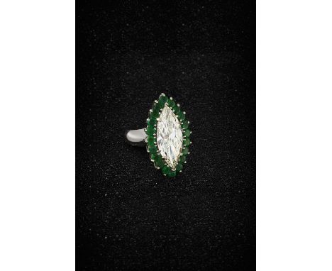 DIAMOND AND EMERALD DRESS RINGThe marquise-cut diamond, weighing 8.72 carats, within a surround of circular-cut emeralds, rin