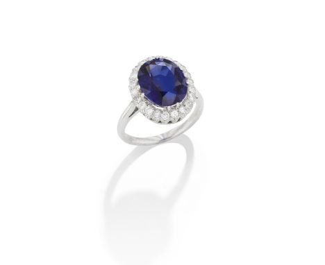 SAPPHIRE AND DIAMOND CLUSTER RINGThe oval-cut sapphire, weighing 5.44 carats, within a brilliant-cut diamond surround, ring s