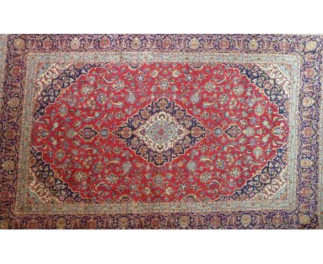 A Central Persian Kashan carpet, central double pendent medallion with repeating spandrels on a rouge field, within stylised 